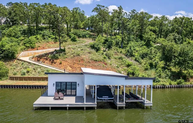 a view of a swimming pool with lawn chairs plants and lake view