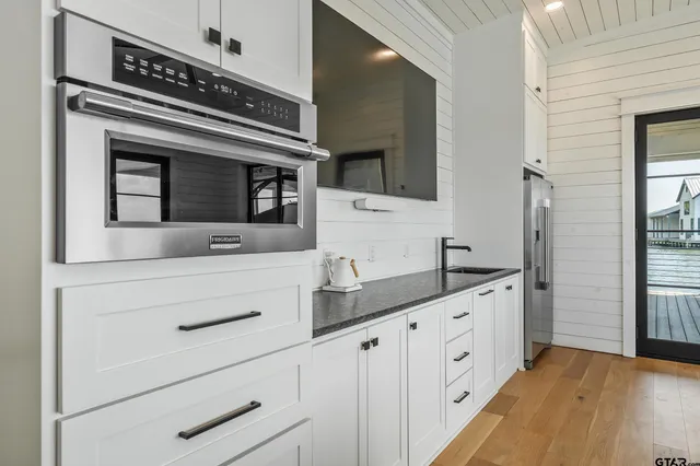 a kitchen with granite countertop white cabinets and stainless steel appliances