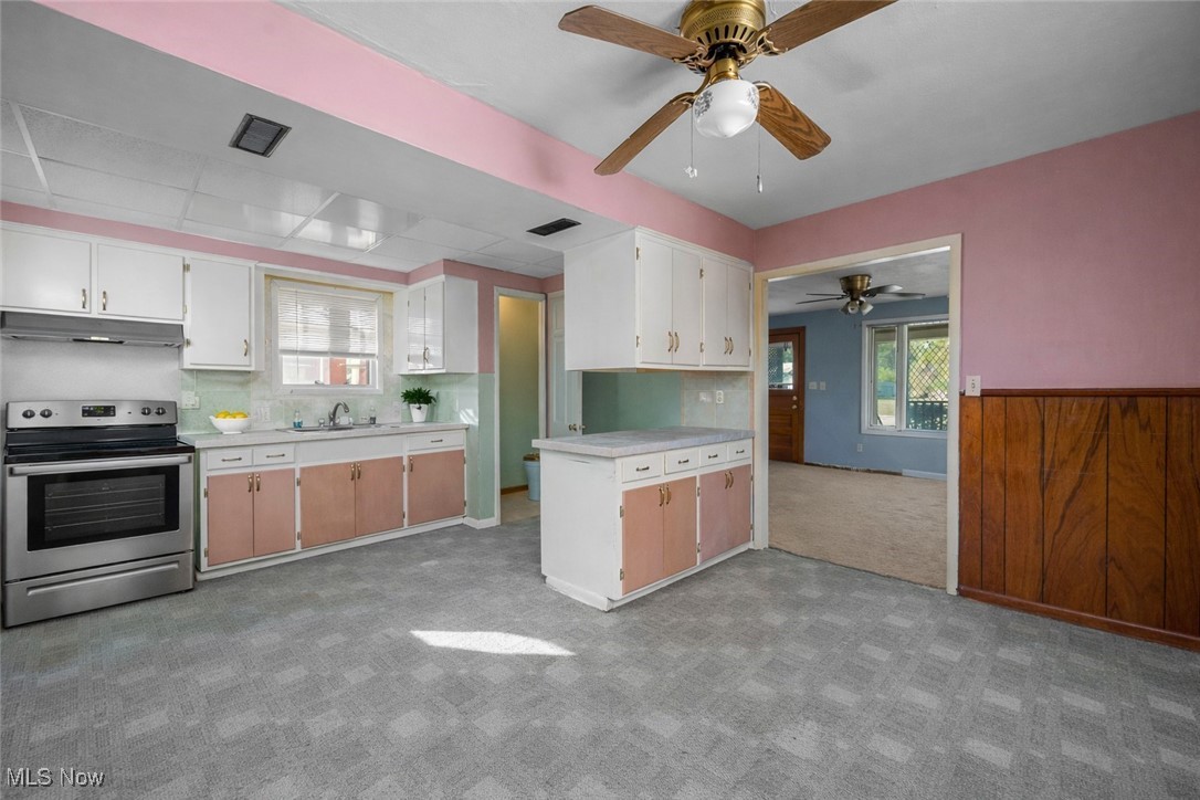6927 North Wildacre Road Curtice, OH 43412 - Photo 7 of 44 Kitchen featuring stainless steel electric range, light countertops, healthy amount of natural light, and light colored carpet