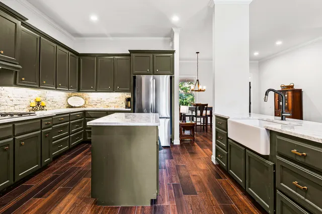 a kitchen with stainless steel appliances granite countertop a refrigerator a sink dishwasher a stove and white countertops with wooden floor