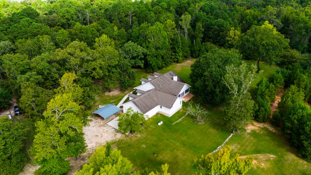 an aerial view of residential houses with outdoor space and trees all around