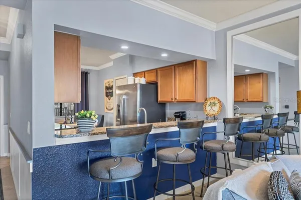 a living room with lots of furniture kitchen view and a wooden floor