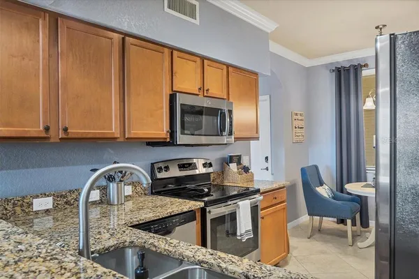 a kitchen with stainless steel appliances granite countertop a stove top oven a sink dishwasher and cabinets with wooden floor