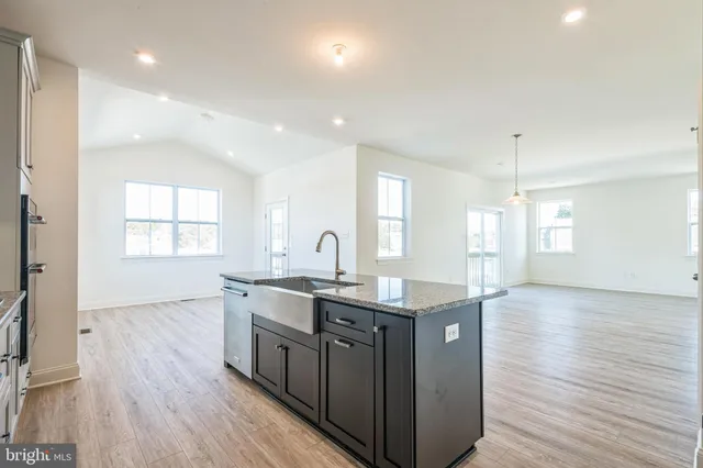 a kitchen with stainless steel appliances granite countertop wooden floors and white cabinets