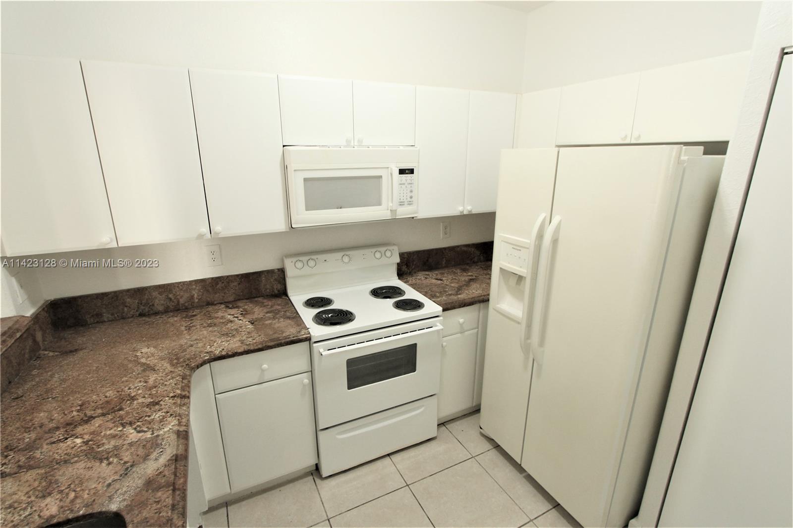1652 Southeast 28th Street, Unit 105 Homestead, FL 33035 - Photo 4 of 18 a kitchen with white cabinets and white appliances