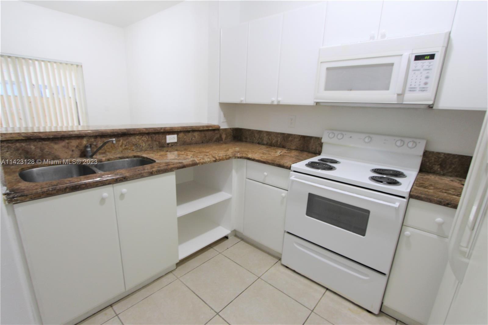 1652 Southeast 28th Street, Unit 105 Homestead, FL 33035 - Photo 5 of 18 a kitchen with white cabinets and white appliances