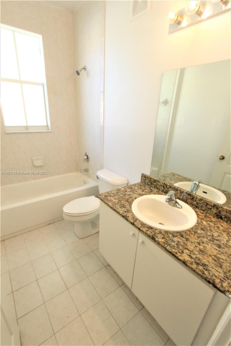 1652 Southeast 28th Street, Unit 105 Homestead, FL 33035 - Photo 9 of 18 a bathroom with a granite countertop sink a toilet and a bathtub