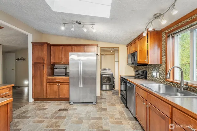 a kitchen with stainless steel appliances granite countertop a refrigerator a stove top oven a sink and dishwasher