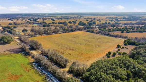 an aerial view of residential houses with outdoor space and trees