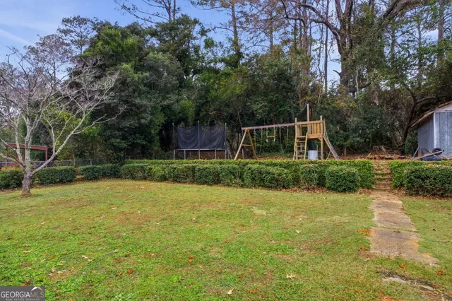a view of a backyard with potted plants and large trees