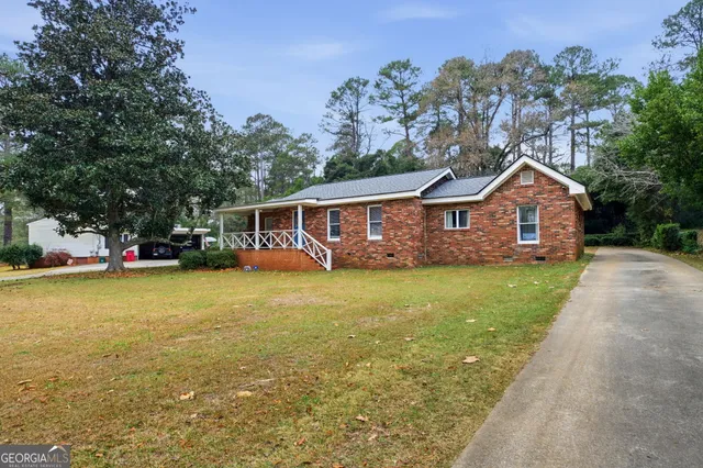 a front view of house with yard and trees in the background