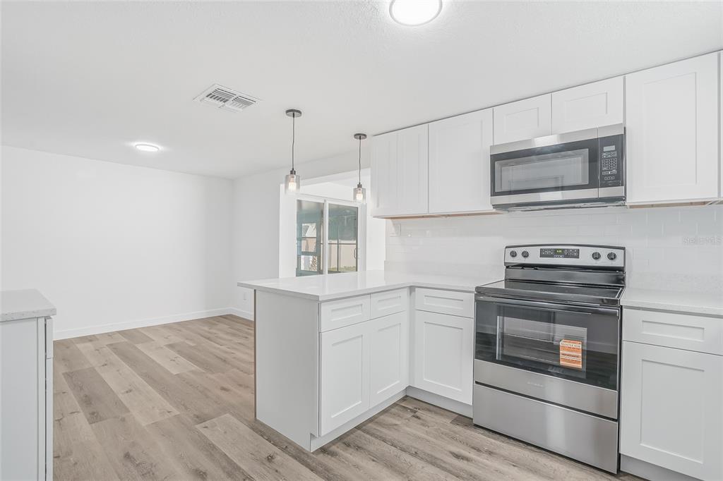 7840 Gulf Way Hudson, FL 34667 - Photo 11 of 37 a kitchen with stainless steel appliances granite countertop a stove and a microwave
