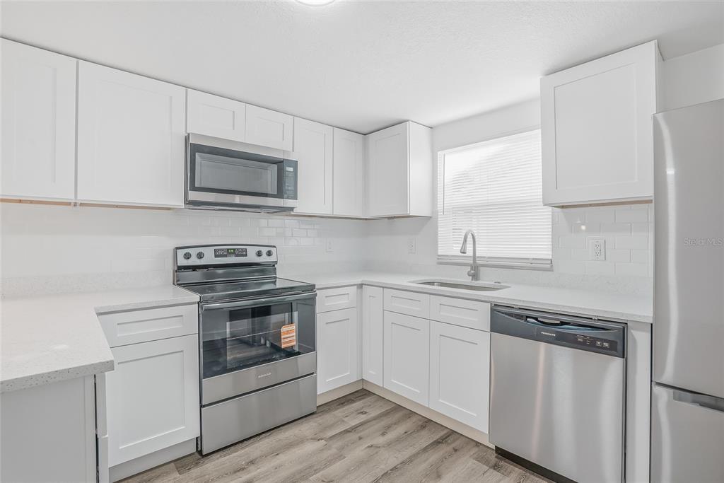 7840 Gulf Way Hudson, FL 34667 - Photo 9 of 37 a kitchen with stainless steel appliances granite countertop white cabinets a sink a stove a microwave and cabinetry