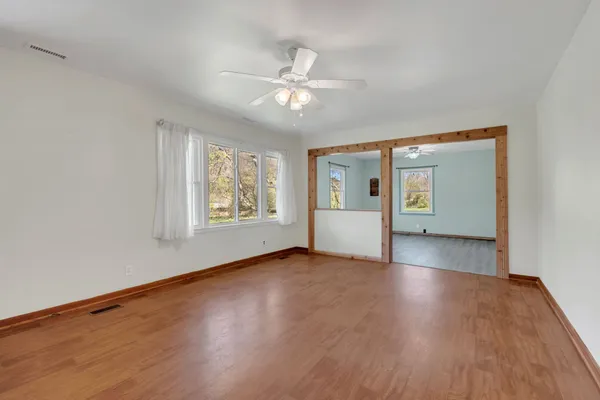 a view of an empty room with a window and wooden floor