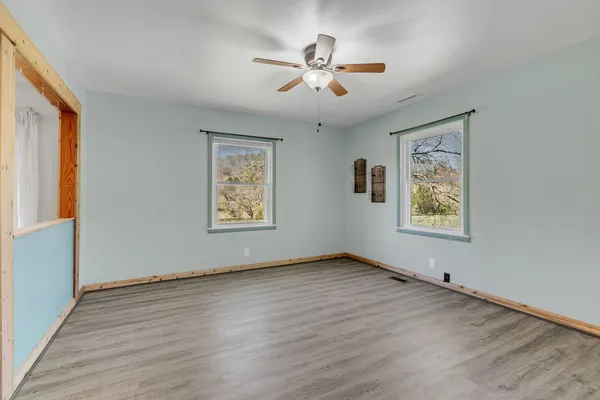 a large kitchen with granite countertop a refrigerator a sink dishwasher a stove and white cabinets with wooden floor