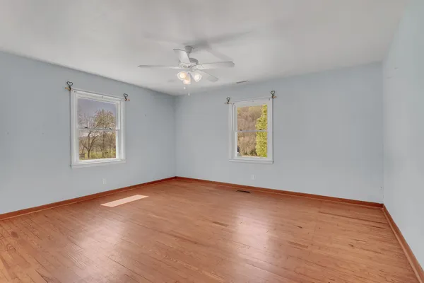 a view of an empty room with wooden floor and a window