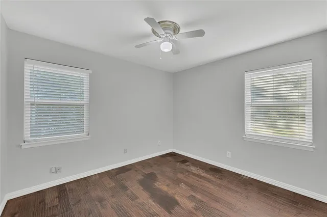 a view of an empty room with a window and a ceiling fan