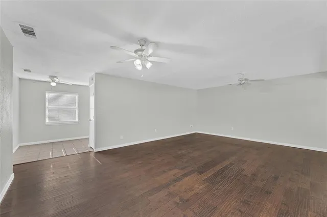 an empty room with wooden floor and ceiling fan
