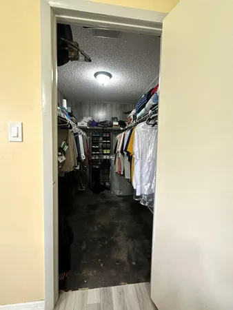 a spacious bedroom with a bed a chandelier and dresser