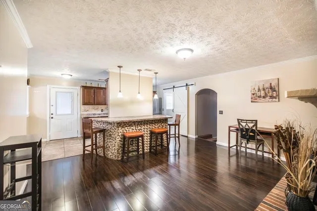a dining room with furniture wooden floor a rug and a kitchen