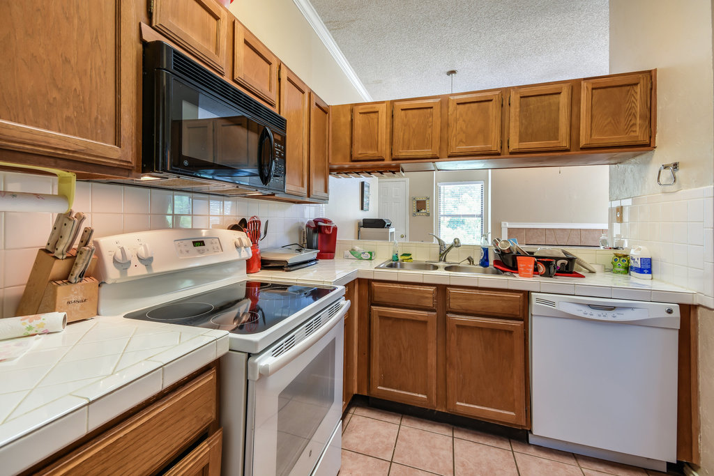 2802 Nueces Street, Unit 312 Austin, TX 78705 - Photo 12 of 22 a kitchen with stainless steel appliances granite countertop a sink dishwasher stove and microwave with wooden cabinets