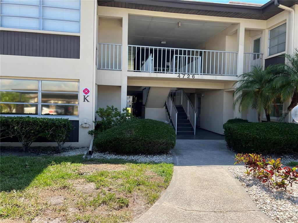 4726 Marine Parkway, Unit 104 New Port Richey, FL 34652 - Photo 2 of 19 a view of a house with a small yard plants and a large tree