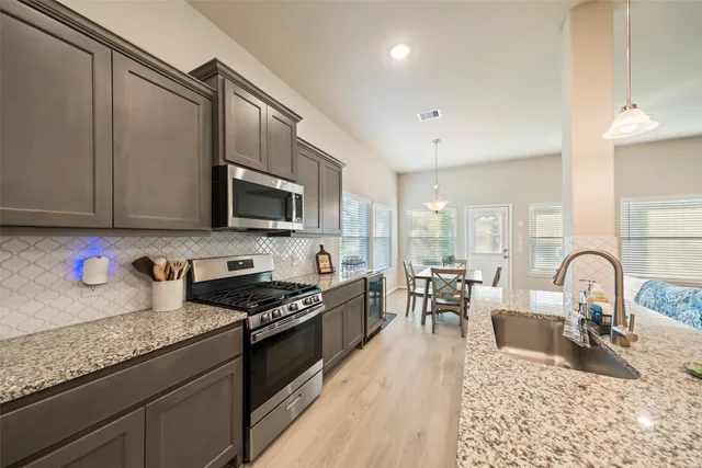 a kitchen with granite countertop a stove a sink a dining table and chairs