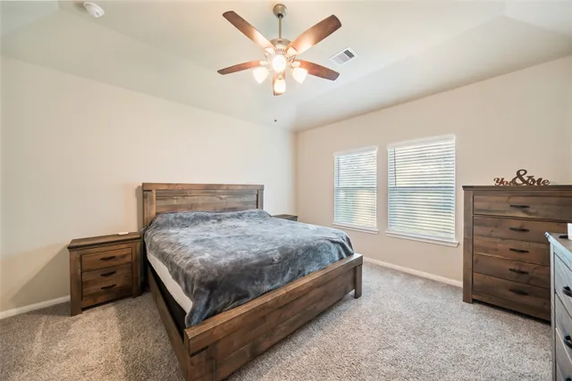 a spacious bedroom with a bed and a ceiling fan