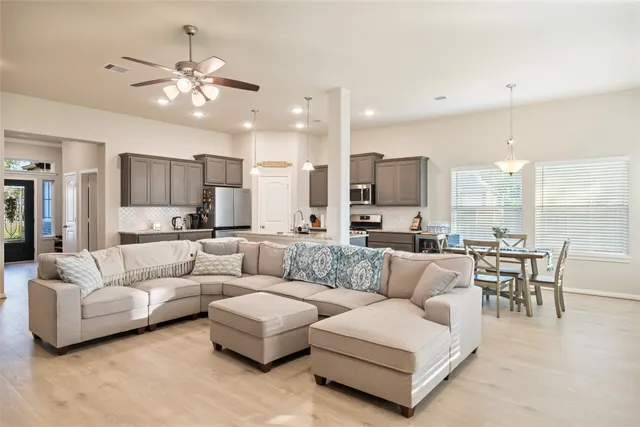 a living room with furniture kitchen area and a chandelier