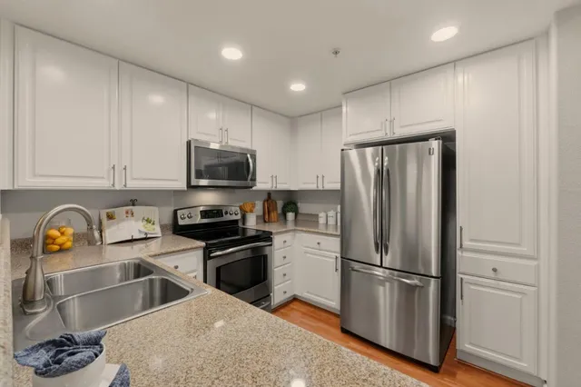 a kitchen with stainless steel appliances granite countertop a refrigerator a stove a sink and a microwave