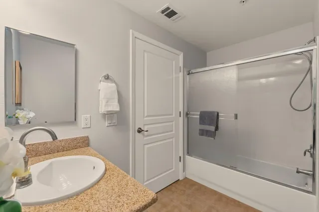 a bathroom with a granite countertop sink a mirror and shower