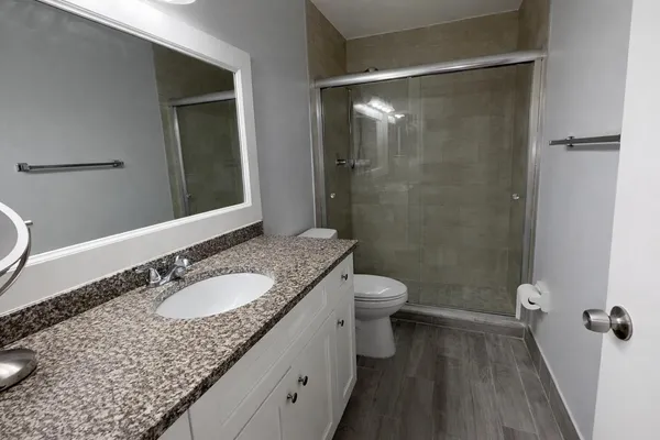 a bathroom with a granite countertop sink toilet and shower