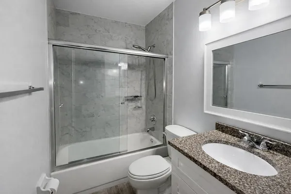 a bathroom with a granite countertop sink toilet mirror and shower