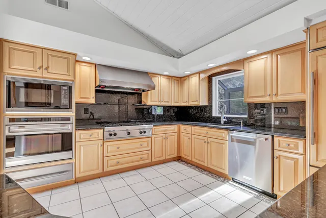 a kitchen with granite countertop white cabinets stainless steel appliances and a window