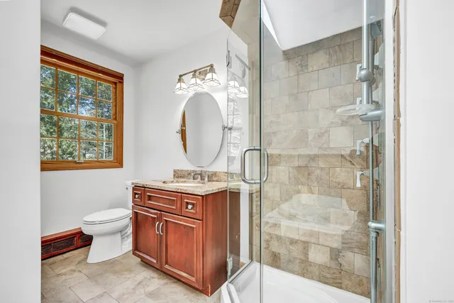 a bathroom with a granite countertop toilet a sink and a mirror