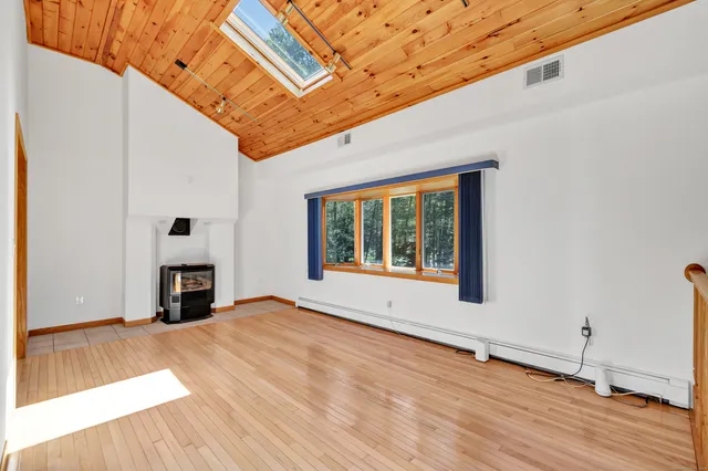 a view of an empty room with window and wooden floor