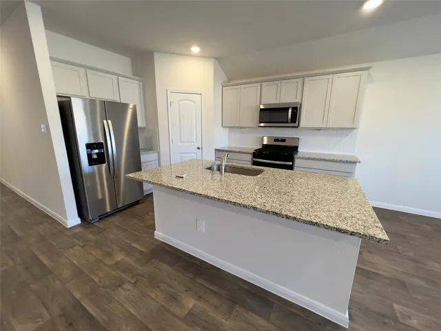 a kitchen with granite countertop a refrigerator and a sink