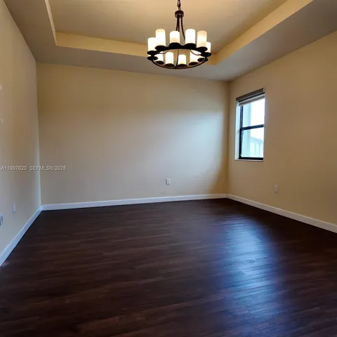 a view of empty room with wooden floor and window