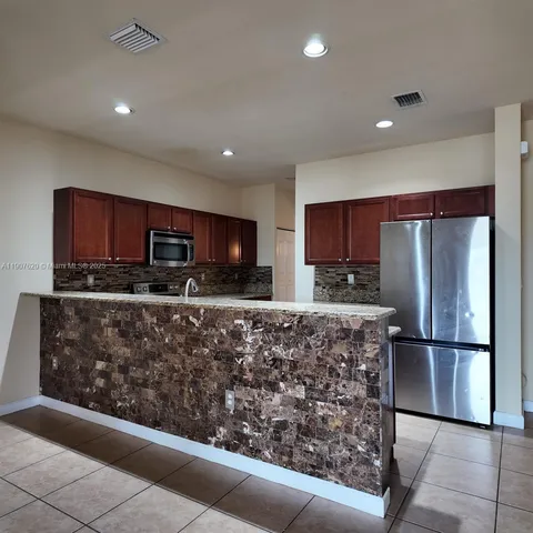 a kitchen with stainless steel appliances granite countertop a refrigerator and a microwave