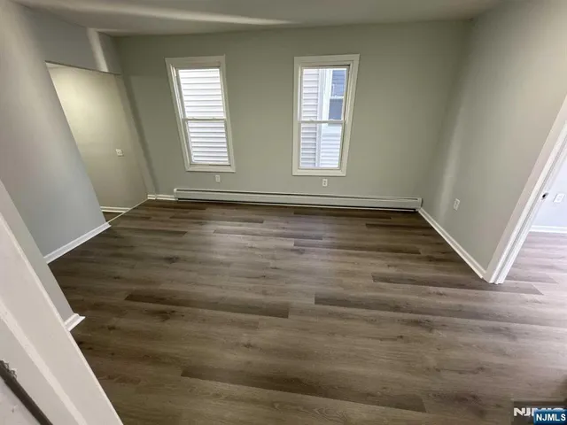 a view of an empty room with wooden floor and window