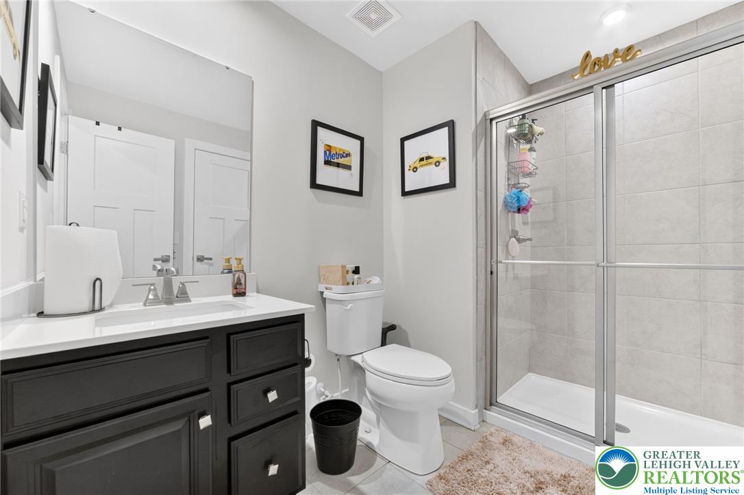 3952 Orth Street Bethlehem, PA 18020 - Photo 47 of 60 A well-appointed bathroom features a dark wood vanity, white countertop, and a sleek shower with glass enclosure.