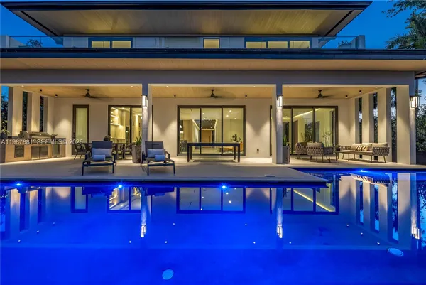 a view of swimming pool with red chairs in front of house