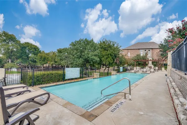 a view of a swimming pool and lounge chairs in back yard of the house