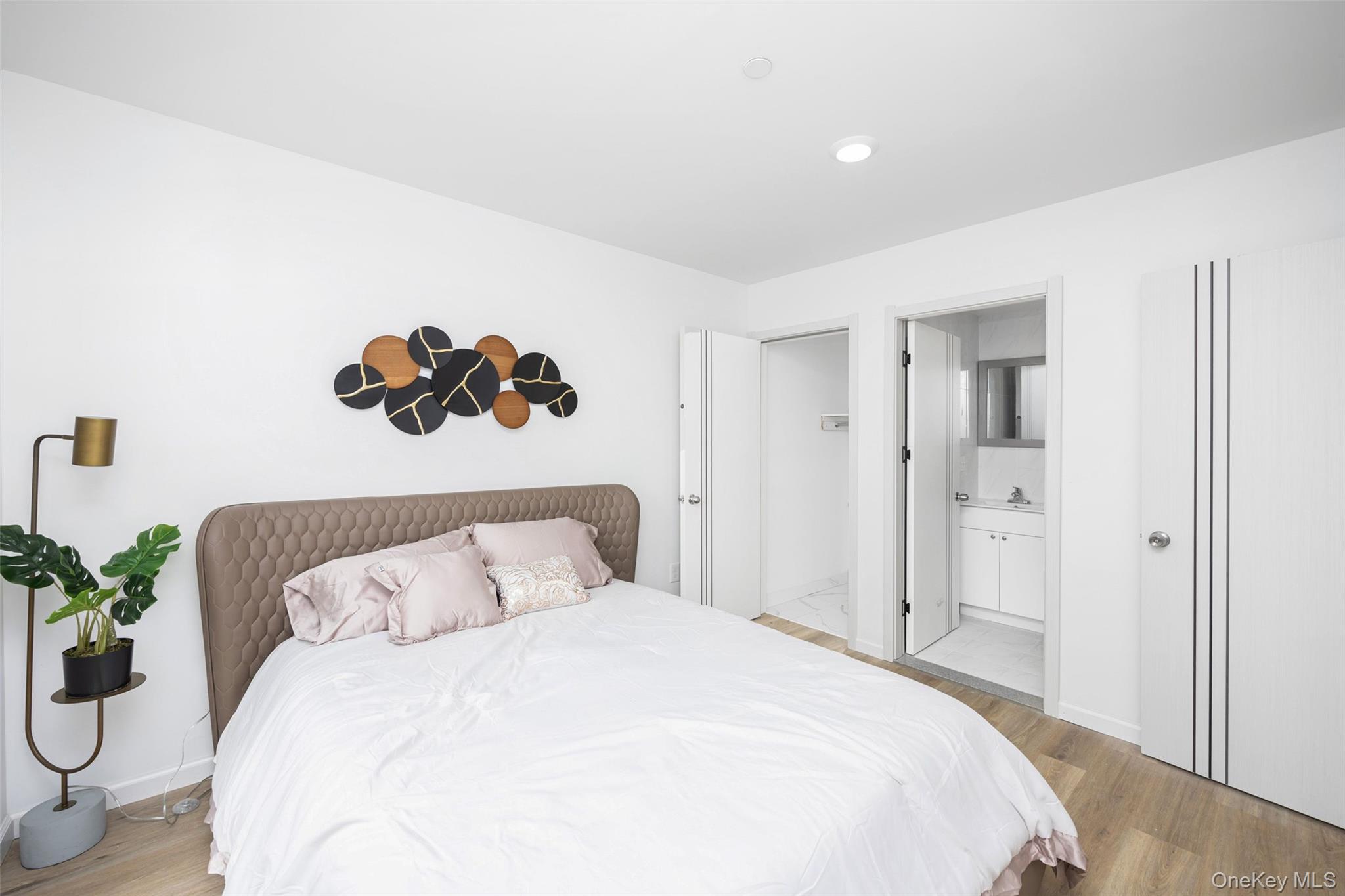 70-40 45th Avenue, Unit 8I Queens, NY 11377 - Photo 4 of 5 Bedroom featuring light wood-type flooring and ensuite bath