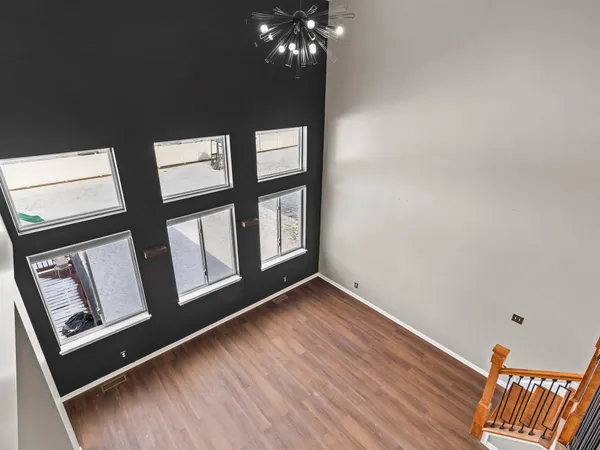 a view of an empty room with wooden floor and windows
