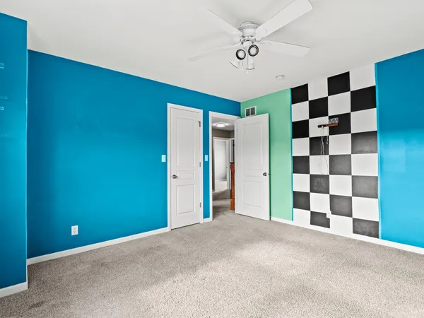 a view of a big room with a large window and a ceiling fan