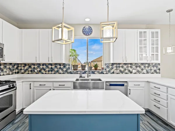 a kitchen with kitchen island granite countertop a sink and white cabinets