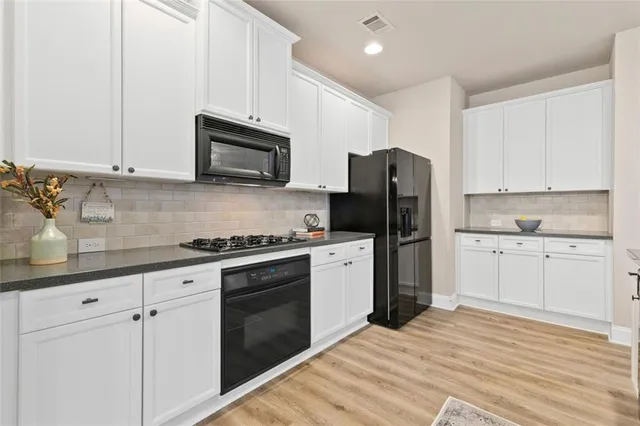 a kitchen with granite countertop white cabinets and stainless steel appliances