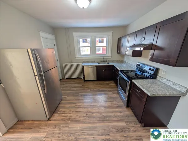 a kitchen with stainless steel appliances granite countertop a refrigerator a sink a stove a washer dryer and a refrigerator