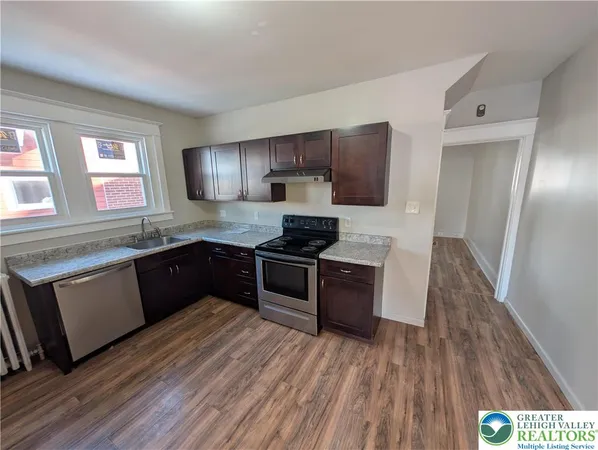 a kitchen with granite countertop wooden floors a stove and a microwave